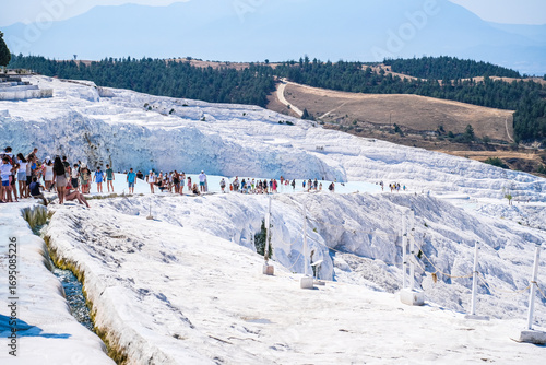 Group of people enjoying the unique white terraces of Pamukkale in Turkey. Natural thermal pools and travertine formations.