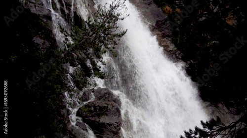 Slow motion, a big waterfall in the rocks on a sunny day in Pyrenees, Spain.