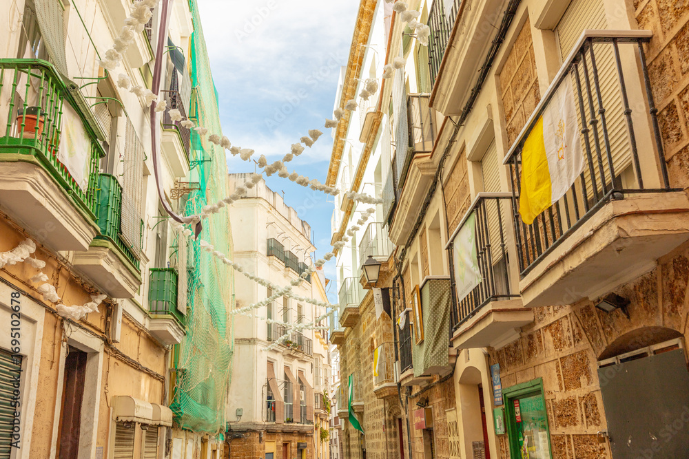 Fototapeta premium Traditional stone residential building with green balconies and palms in Cadiz, Andalusia, Spain, September 2025.