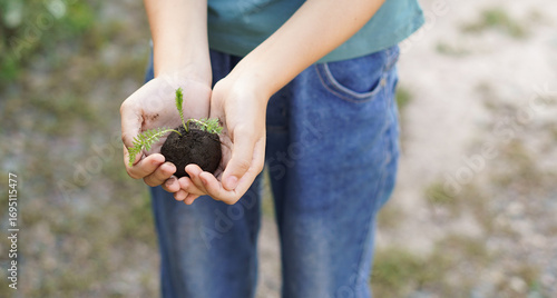 child holds a seed ball with a sprout on the background of an empty earth. earth balls. nendo dango. Guerrilla gardening