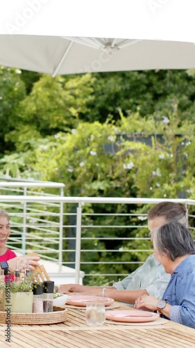 Wallpaper Mural Chatting Diverse female friends sitting around table on deck, with bread basket and patio umbrella Torontodigital.ca