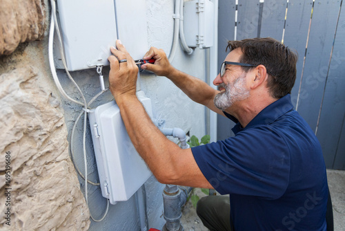 Home inspector opening an electrical panel outside a home