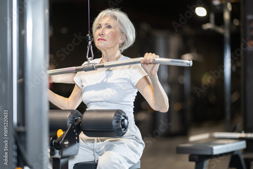 Quadro su tela Motivated senior woman maintaining active and healthy lifestyle working out at g