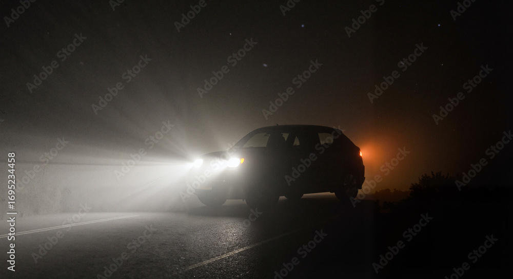Obraz premium Car headlights illuminating road in foggy night scenery