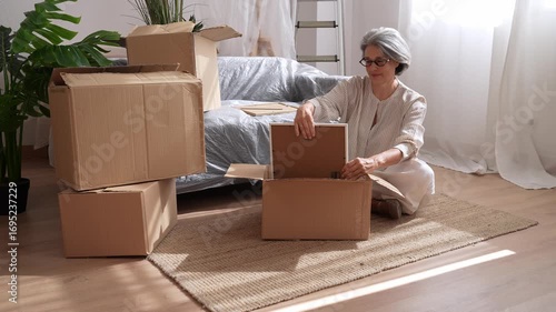 Senior woman packing picture frame into cardboard box