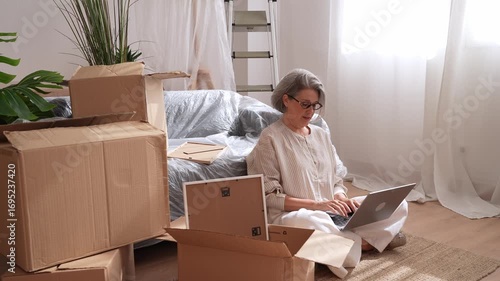 Senior woman managing relocation logistics on laptop