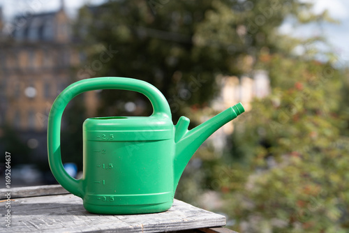 Green Plastic Watering Can on a Wooden Table Outdoors