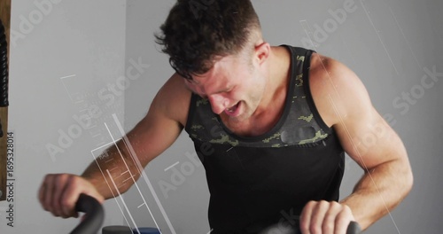 Принти на полотні Pedaling muscular enthusiast riding stationary exercise bike in home studio with