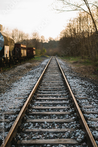 Empty railway track with sunset light and abandoned train cars