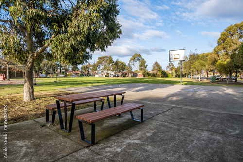 Public park with picnic tables, benches, and a basketball hoop in a suburban neighborhood of Melbourne, Australia. Concept of outdoor recreation, community facilities, and family-friendly spaces.