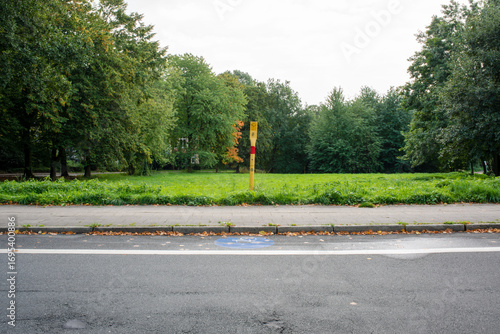 Yellow marker post in a park meadow with sidewalk foreground