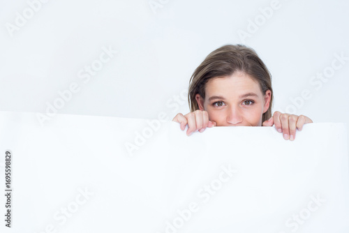 Canvas Print Woman peeking over large blank white panel in studio, framing minimalist backdro