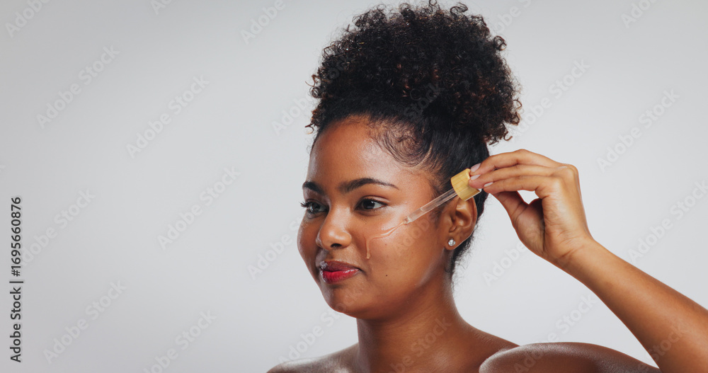 Fototapeta premium Beauty, skincare and woman with serum in studio for hydration, hyaluronic acid or skin benefits. Dropper, black person or apply vitamin c on white background for face elasticity, glow or mockup space