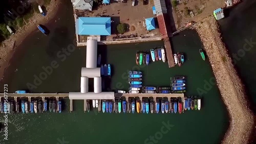 Aerial view of Sofifi harbor with speed boats docked and departing, showing sea transportation hub in North Maluku, Indonesia.