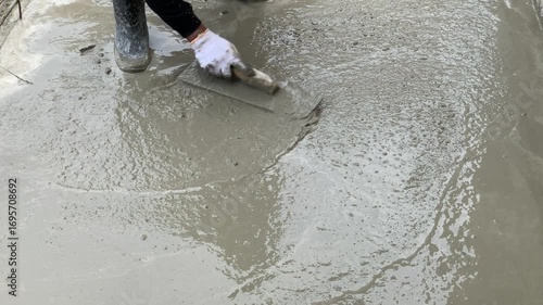 4K footage of construction worker leveling wet cement mix with trowel, close-up hand in white glove. Strong detail of building process, perfect for construction, industry, labor, and teamwork themes.
