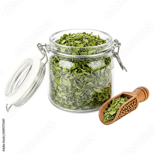 Dried moringa leaves in glass jar with wooden scoop