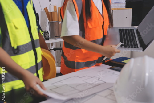 Closeup of team of industrial engineers meeting analyze machinery blueprints consult project on table in manufacturing factory. Working in manufacturing plant or production plant.