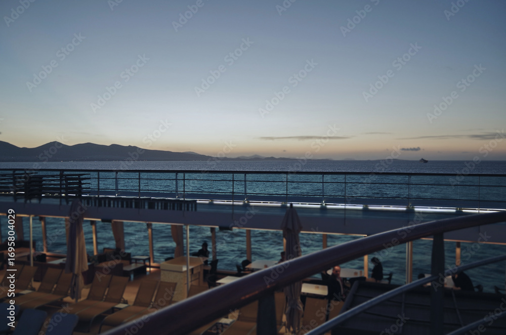 Fototapeta premium Pooldeck or swimmingpool with sun deck on modern cruiseship or cruise ship liner with elegant lounge furniture deck chairs and rattan sun beds loungers