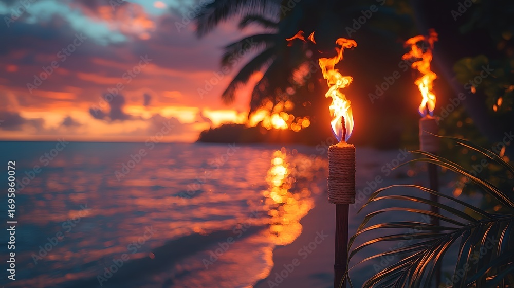 Fototapeta premium Two tiki torches burn brightly on a tropical beach at sunset illuminating the serene ocean waves and colorful sky