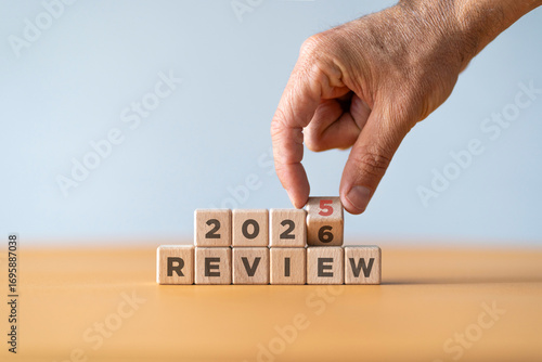 Hand flipping of 2025 to 2026 on wooden blocks. 2025 business and customer review for business strategic planning in the next year 2026. End of the year business concept.