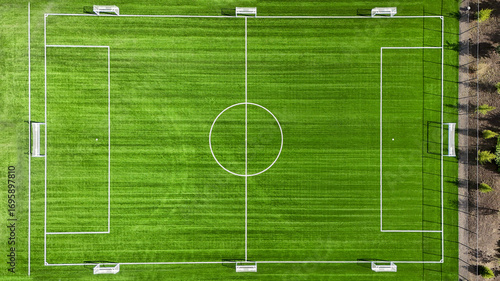 A soccer field with a white goal and a white circle in the middle. The field is green and well maintained