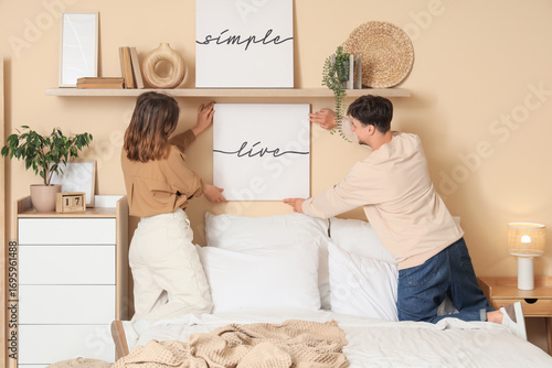 Young couple hanging poster...