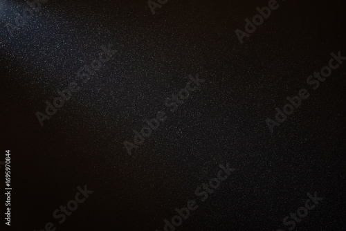 Fototapeta Light beam illuminating countless dust particles floating in the air against a b