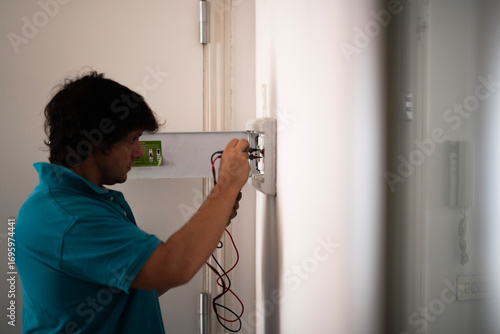 Photography A man uses a clamp meter to check circuit breakers and the differential in an electrical panel
