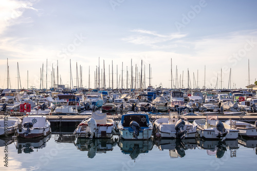 panoramic view of marina with yachts, ships, boats and sailboats under soft clear sky in golden hour in warm tones