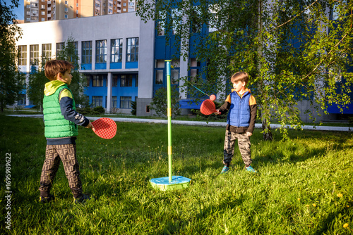 Two friends are playing tetherball swing ball game in summer camping. Two boy brother happy leisure healthy active time outdoors concept