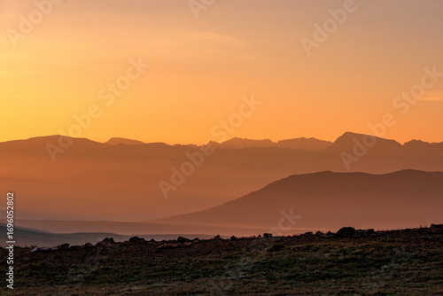 Wallpaper Mural View of hazy, mountainous silhouettes fading into the warm orange glow of the sunset, creating a serene and majestic vista , Deosai National Park, Gilgit Baltistan, Pakistan. Torontodigital.ca