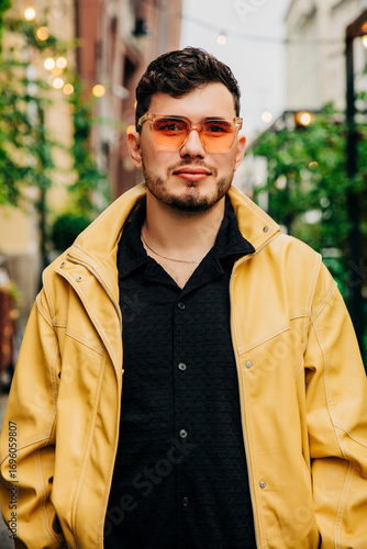 Stylish urban man in yellow jacket with sunglasses during evening outing