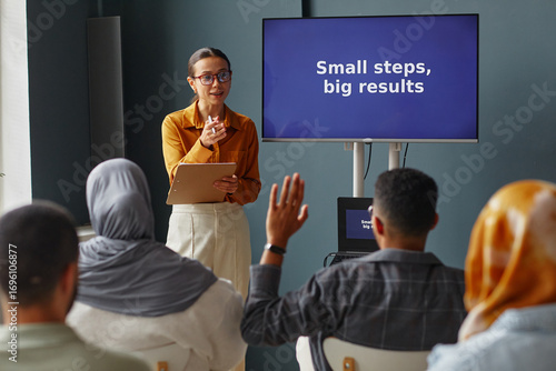 Принти на полотні Young adult Caucasian woman standing in front of screen holding clipboard, teach