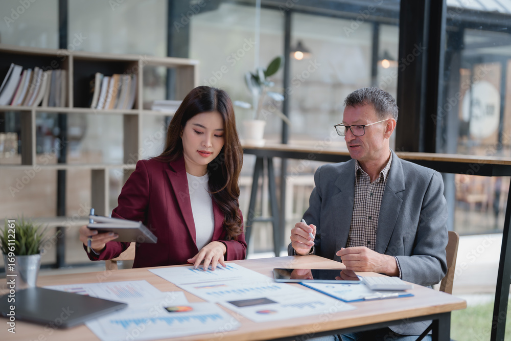 Fototapeta premium Two business partners working together on company financial strategy analyzing charts and graphs using laptop and digital tablet discussing marketing during meeting