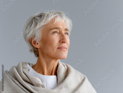 Hopeful senior woman looking up on gray background