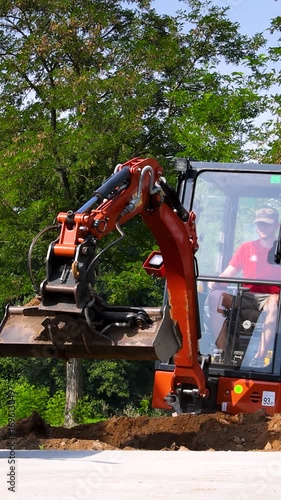 Mini excavator backfilling a trench with soil
