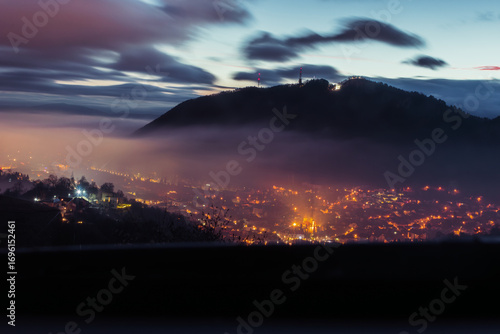Brasov cityscape at morning with fog and glowing lights from Belvedere