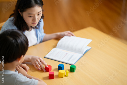 Wallpaper Mural Speech Therapist Guiding Boy With Colorful Blocks at Desk, Child Development Torontodigital.ca