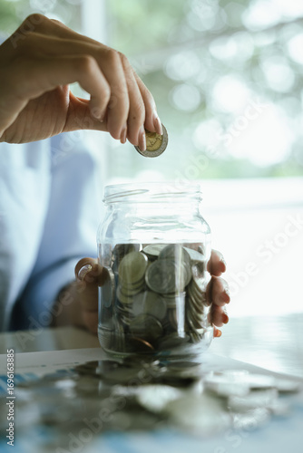 An adult holds a coin, which symbolizes finance, investing, saving, retirement planning, profits, banking, growth, success, and long-term financial stability.