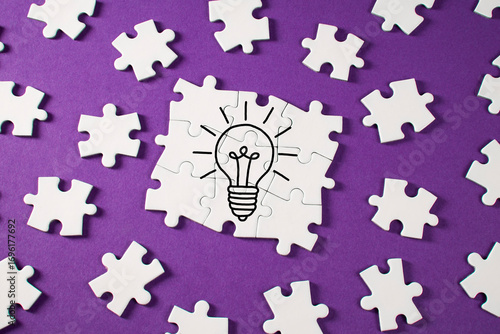 Light bulb with puzzle pieces on purple background	