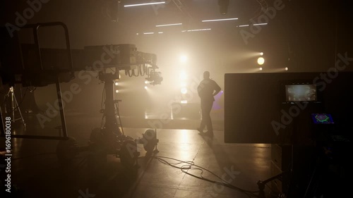 Silhouette of a man standing on a foggy studio set, dramatically backlit by bright golden lights, conveying themes of leadership, mystery, and cinematic production