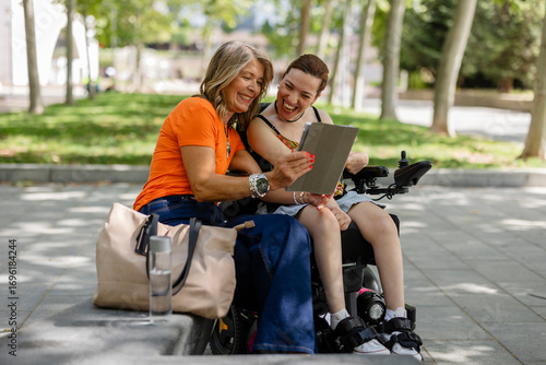 Volunteer helping disabled woman using tablet in park