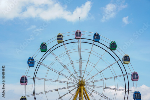 A ferris wheel with colorful cabins standing tall under the blue sky.