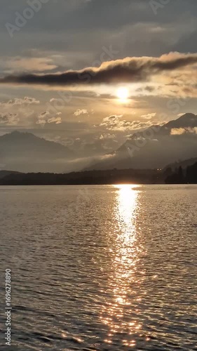 Peaceful orange sunset at a lake with mountains and perfect water reflections.