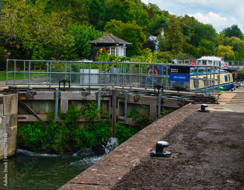 Fotografi Narrow boat waiting for river levels to equalize in Marsh lock on the River Tham