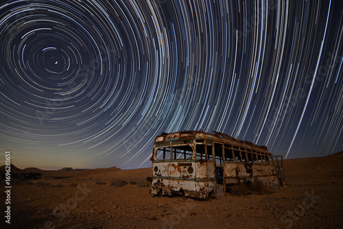 abandoned bus in the desert with star trails