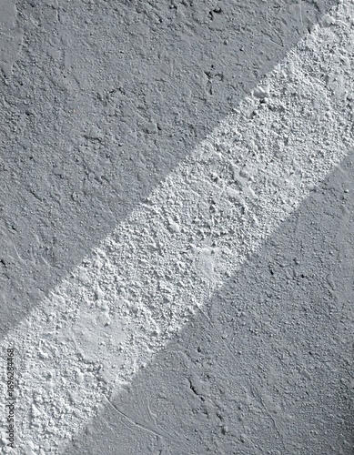 A textured concrete surface displays a diagonal stripe of contrasting white paint.