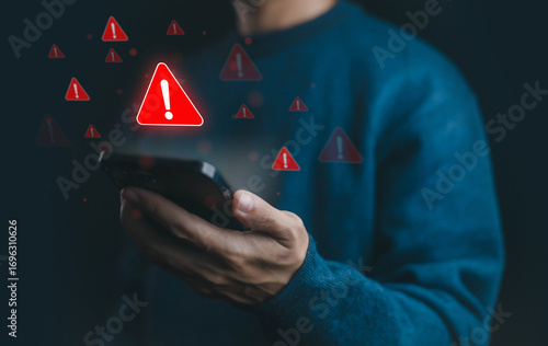 Man holding smartphone with warning alert icon, symbolizing cyber security threat, mobile malware, phishing scam, data breach, online fraud, and digital safety risk notification.
