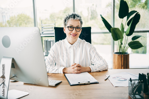 Confident mature businesswoman in a bright office setting working on professional tasks while sitting at her desk