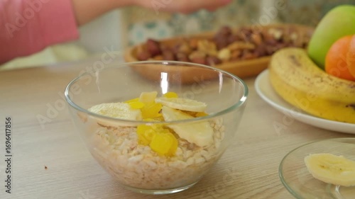 Close-up of a child hands adding nuts to a bowl of oats for a healthy breakfast. Emphasizes wellness and a nutritious diet